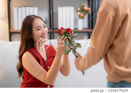 Happy asian woman receiving rose bouquet from boyfriend with celebrating Valentine's Day. Happy asian woman receiving rose bouquet from boyfriend with celebrating Valentine's Day. 135677029