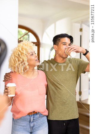 Young friends enjoying coffee together at home, smiling and embracing warmly 135677211