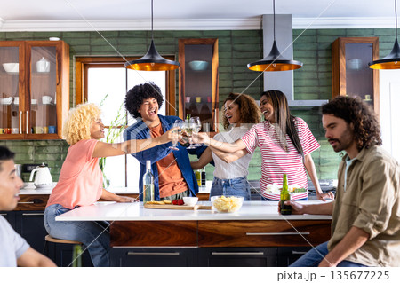 In kitchen, friends raising glasses and celebrating casual gathering together In kitchen, friends raising glasses and celebrating casual gathering together 135677225