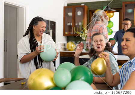 Seniors holding colorful balloons, having lively gathering with friends at home 135677299