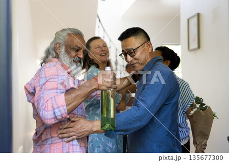 Senior friends exchanging gifts and laughter, cherishing joyful moments at home Senior friends exchanging gifts and laughter, cherishing joyful moments at home 135677300