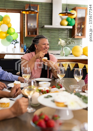 At party, senior woman having cupcake and chatting with friends At party, senior woman having cupcake and chatting with friends 135677344