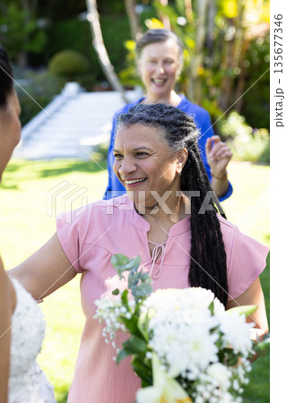 Celebrating with friends, senior woman holding bouquet at garden event outdoors Celebrating with friends, senior woman holding bouquet at garden event outdoors 135677346