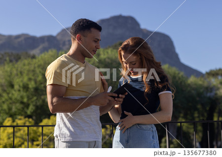Young couple enjoying outdoor view while looking at smartphone together Young couple enjoying outdoor view while looking at smartphone together 135677380