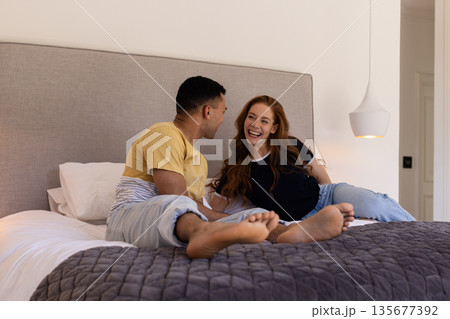 Young couple laughing and relaxing together on cozy bed at home 135677392