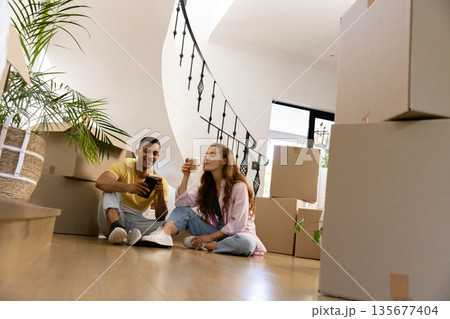 Young couple enjoying coffee break while unpacking boxes in new home 135677404