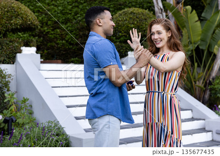 Young couple joyfully celebrating engagement outdoors, holding hands and smiling Young couple joyfully celebrating engagement outdoors, holding hands and smiling 135677435