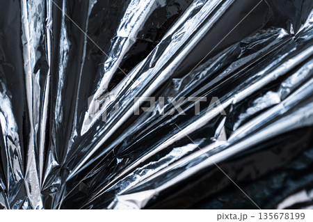 Abstract metallic foil texture with sharp diagonal folds and reflections 135678199