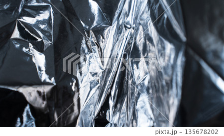 Close-up metallic foil texture with complex layered reflections 135678202