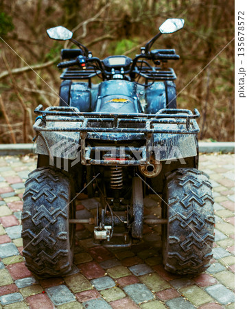 Rear view of a dirty all-terrain vehicle parked outside after off-road riding. Mud splashes on the body emphasize adventure, power, and outdoor motorsport lifestyle. 135678572