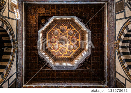 Intricate ceiling design of Sultan Al-Ashraf Qaytbay Mosque. Features geometric patterns and ornate details in gold and brown tones 135678681