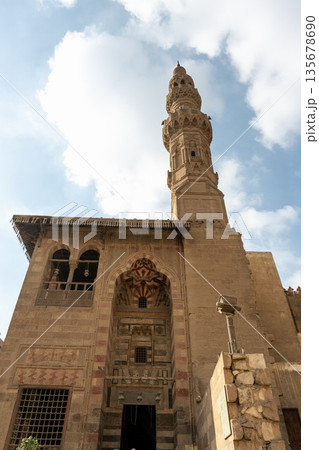 Sultan Al-Ashraf Qaytbay Mosque and mausoleum features intricate architecture with a tall minaret and detailed stonework under a blue sky. Sultan Al-Ashraf Qaytbay Mosque and mausoleum features intricate architecture with a tall minaret and detailed stonework under a blue sky. 135678690