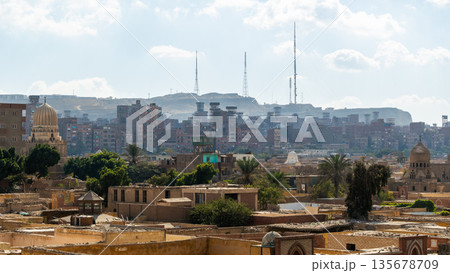 A panoramic view of the City of the Dead in Cairo, featuring ancient tombs, mosques, and minarets under a clear blue sky. 135678709