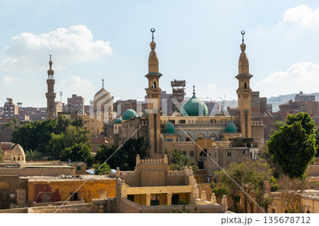 A panoramic view of the City of the Dead in Cairo, featuring ancient tombs, mosques, and minarets under a clear blue sky. A panoramic view of the City of the Dead in Cairo, featuring ancient tombs, mosques, and minarets under a clear blue sky. 135678712