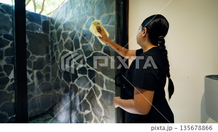 Cleaning lady wiping glass shower door in costa rica 135678866