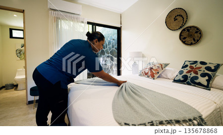 Housekeeper preparing luxurious hotel bedroom in costa rica Housekeeper preparing luxurious hotel bedroom in costa rica 135678868