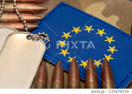 Ammunition and army tags on blue fabric with European Union symbols. Ammunition and army tags on blue fabric with European Union symbols. 135679259