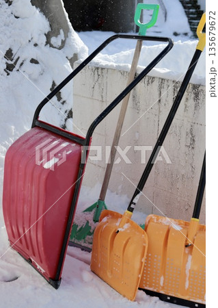 雪が積もった塀に立てかけたママさんダンプとスコップ 雪が積もった塀に立てかけたママさんダンプとスコップ 135679672