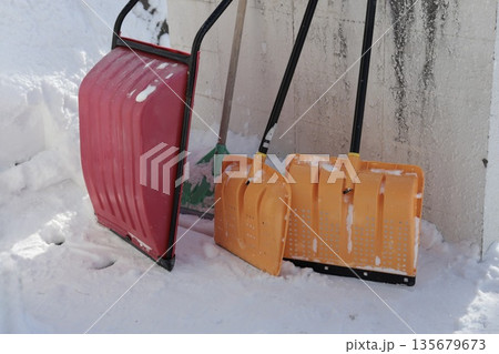 雪が積もった塀に立てかけたママさんダンプとスコップ 雪が積もった塀に立てかけたママさんダンプとスコップ 135679673