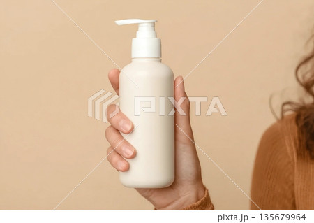 Woman with shampoo bottle on beige background, closeup Woman with shampoo bottle on beige background, closeup 135679964