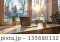 Cozy home office setup with laptop, plants, and coffee cup on wooden desk by sunlit window 135680132