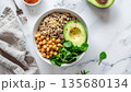 Healthy bowl with quinoa, chickpeas, avocado, and spinach on marble surface 135680134
