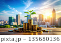 Small plant growing from stacked coins symbolizes financial growth and investment success against city skyline at sunrise 135680136