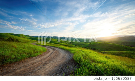 Dirt Road Through Green Rolling Hills at Sunrise 135680587