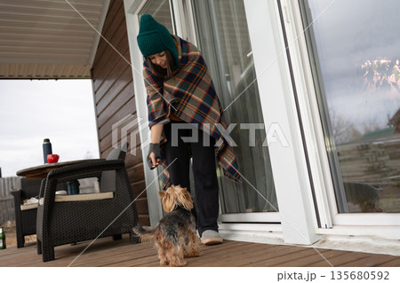 Young Woman Playing With a Yorkshire Terrier on Her Porch in Autumn 135680592