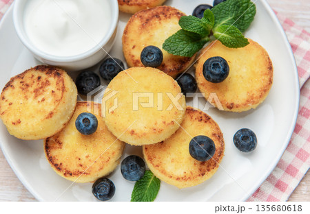 Syrniki cottage cheese pancakes served with blueberries and sour cream 135680618