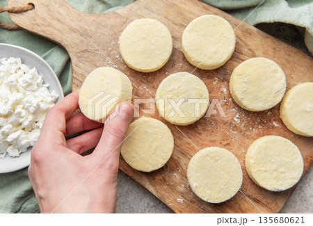 Preparing syrniki cottage cheese pancakes on cutting board 135680621