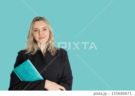 Business Woman Holding a Diary in Her Hands While Standing in Front of a Plain Background 135680671