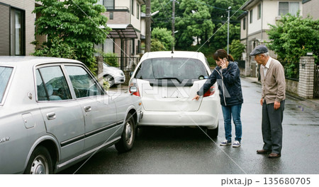 住宅街で発生した自動車の物損事故 凹みを確認し保険手続きを行う人物と高齢者 リアル 3DCG 135680705