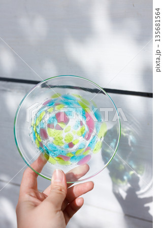 柔らかな木漏れ日の中でガラスプレートを手に取る女性の手 柔らかな木漏れ日の中でガラスプレートを手に取る女性の手 135681564