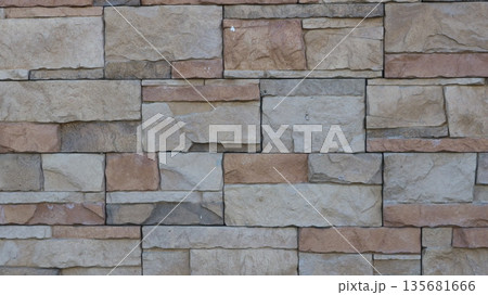 A fragment of a tiled wall made of natural stone, a mosaic of square shapes of different sizes in a gray-brown color scheme, decorative stone finishing tiles in the design of exterior surfaces A fragment of a tiled wall made of natural stone, a mosaic of square shapes of different sizes in a gray-brown color scheme, decorative stone finishing tiles in the design of exterior surfaces 135681666