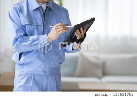 タブレットに入力する作業服を着たの男性の手元 135681762