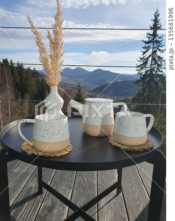 Two cups of tea on a coffee pot on a small table on a terrace with a view of the Carpathian Mountains. Two cups of tea on a coffee pot on a small table on a terrace with a view of the Carpathian Mountains. 135681996