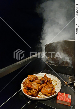 On the terrace, barbecue is being prepared on the grill, smoke is in the air and there is a cozy mood On the terrace, barbecue is being prepared on the grill, smoke is in the air and there is a cozy mood 135682001