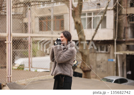 Woman sipping coffee in a cozy urban setting during a chilly afternoon 135682742