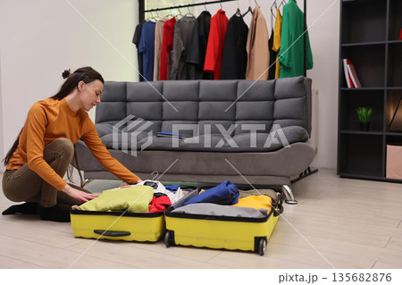 Preparing for a stylish journey with colorful outfits in a cozy living room setting 135682876