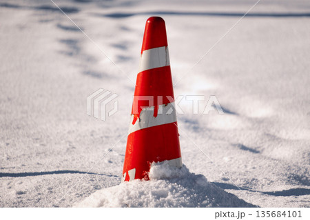 雪原に埋もれた赤いカラーコーン 135684101