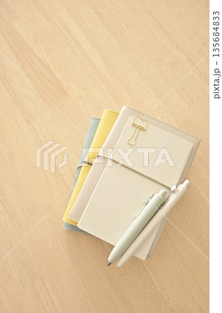 木製の机の上に置かれた手帳とノートとペン 135684833