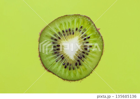 Kiwi slice on green background. Fresh kiwi slice on bright green background showing detailed seeds and juicy flesh. Concept of dieting, nutrition, vitamins, vegetarianism or raw food diet Kiwi slice on green background. Fresh kiwi slice on bright green background showing detailed seeds and juicy flesh. Concept of dieting, nutrition, vitamins, vegetarianism or raw food diet 135685136