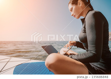 Woman Laptop Ocean - Woman working on her laptop on a boat on the ocean on a sunny day. 135686848