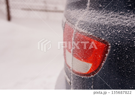 Snow-Covered Car Tail Light in Winter Landscape with Frosty Texture and Red Accents 135687822