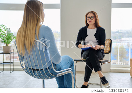 Middle aged professional female psychologist, counselor working with young woman 135688172