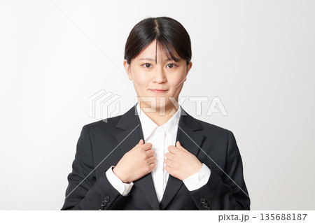 気合いを入れる就活生の女性　スーツ姿で襟を掴むポーズ 135688187