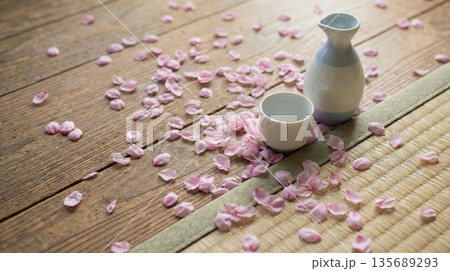 桜の花びらが散りばめられた木製テーブルの上に置かれた徳利とお猪口の晩酌セット 135689293