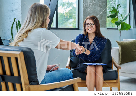 Middle aged professional female psychologist, counselor working with young woman Middle aged professional female psychologist, counselor working with young woman 135689592