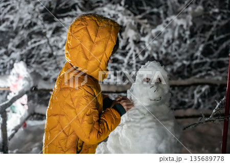 Boy Making a Snowman at Night Boy Making a Snowman at Night 135689778